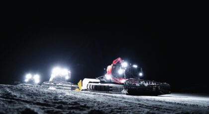 Illuminated snow groomers working at night in Zermatt, Switzerland during winter.