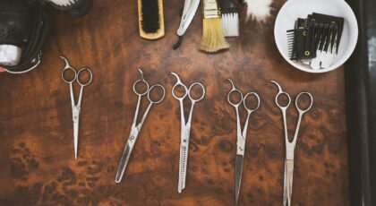A collection of vintage barber tools including scissors and brushes on a wooden surface.