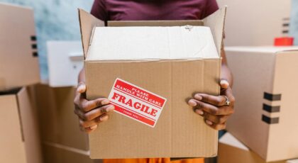 A person holding a cardboard box labeled 'Fragile' during a moving process indoors.