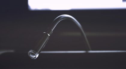 Minimalist close-up of a metallic gooseneck light fixture in dark ambiance.