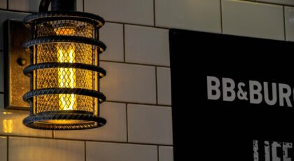 Warmly lit industrial cage lamp against a tiled wall, perfect for cozy indoor environments.