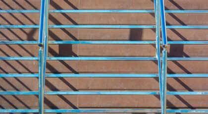 Close-up of a modern staircase featuring metal railings and wooden steps with dramatic shadows.
