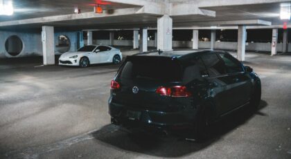 Contemporary prestige automobile parked on asphalt ground lighted with bright shiny lamps