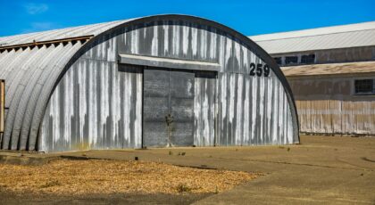 An aged metal warehouse with a curved roof and number 259, showcasing an industrial rustic design.