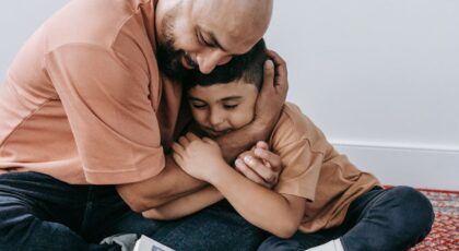 Heartwarming moment of father and son hugging while reading a book together, showcasing love.
