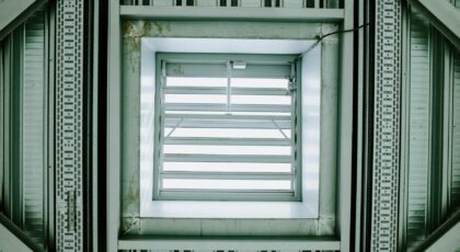 Modern architectural ceiling structure featuring a metallic ventilation grid.