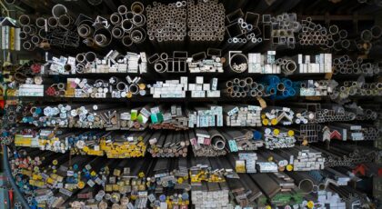 Diverse collection of stacked metallic pipes and rods in a warehouse display.