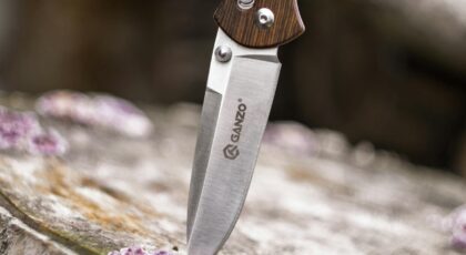 Close-up image of a Ganzo knife embedded in wood, highlighting its sharpness and steel texture.