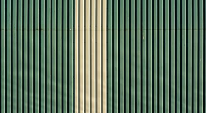 Close-up of a striped green and beige metal wall with vertical patterns.
