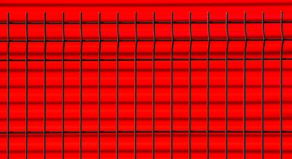 Close-up of a black metal fence against a vibrant red background, creating geometric patterns.