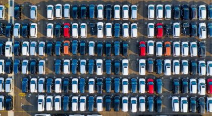 Drone view of various modern vehicles parked on marked parking lot in sunlight