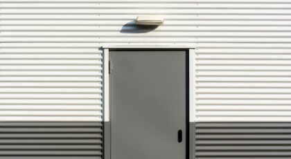 Minimalist image of a corrugated metal wall with a centered door, showcasing industrial architecture.