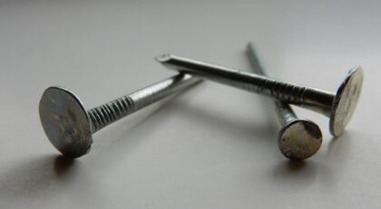 Detailed image of three metallic nails on a white background, highlighting texture and shape.