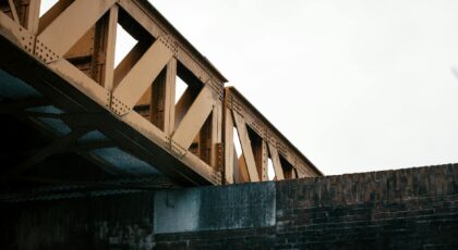 A low angle view of a metal bridge with a brick wall, showcasing industrial architecture.