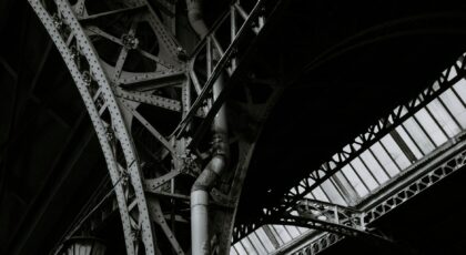 Dramatic black and white photo of steel architecture with geometric patterns and metal pipes.
