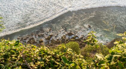 Aerial view of ocean waves crashing on rocks from a cliff in Bali, Indonesia.