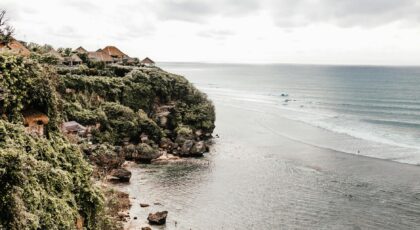 A breathtaking view of lush cliffs and a serene beach with waves gently washing ashore.