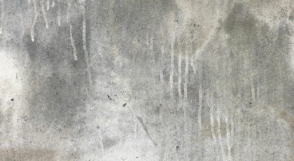 A close-up view of a weathered concrete wall with streaking patterns and texture.