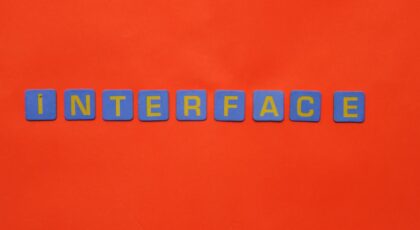 Blue blocks with yellow letters spelling 'INTERFACE' stand out against a vibrant orange backdrop.