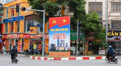 Vibrant Hà Nội street scene featuring a New Year 2026 billboard, motorcycles, and colorful shops.