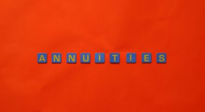 Conceptual image of the word 'Annuities' spelled with tiles on a vibrant red background.