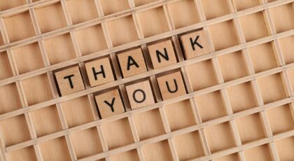 Wooden letter tiles spelling 'thank you' on a grid background, perfect for gratitude themes.