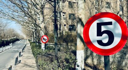 City sidewalk with speed limit and no motorcycles signs under clear blue sky.