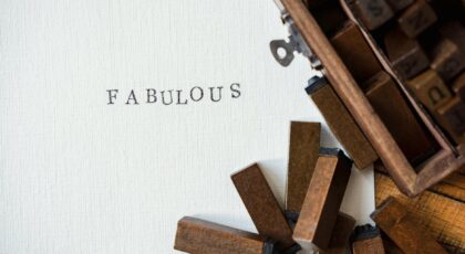 Close-up of wooden letter stamps with 'Fabulous' text on paper, artistic flatlay.