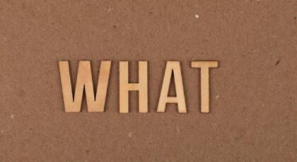 Wooden letters spelling 'What' on a brown cardboard background, close-up view.