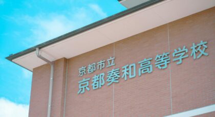Brick building facade with Japanese text under a clear blue sky in Kyoto, Japan.